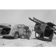 Des hommes du 155e Panzer Artillerie Regiment (Pz.Art.Rgt-155) cuisinent et changent une roue de leur véhicule tandis que des camions passent sur la route