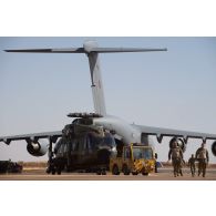 Tractage d'un hélicoptère danois Merlin EH 101 d'un avion-cargo Douglas C-17 britannique sur la piste de Gao, au Mali.