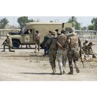 Des soldats irakiens évacuent leur camarade blessé vers une ambulance sous la supervision d'instructeurs à Bagdad, en Irak.