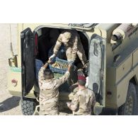 Des soldats irakiens déchargent des munitions à détruire depuis un véhicule blindé à Bagdad, en Irak.