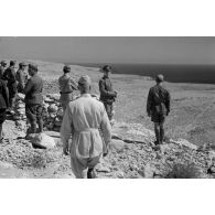 Le général Erwin Rommel, accompagné d'officiers italiens et allemands, observe la mer à partir d'une position retranchée italienne.