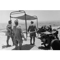 Trois soldats transportent un lit superposé près de deux motos NSU 601 OSL de 600 cc.