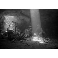 Deux soldats utilisent un téléphone de campagne à l'intérieur d'une grotte où filtre un rayon de lumière.