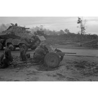 Des soldats sont accroupis près de la route derrière un canon de 3,7 cm PaK en batterie.