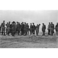 Le groupe d'officiers inspecte une position d'artillerie, il pourrait s'agir d'une position de télémètre camouflée sous un filet.