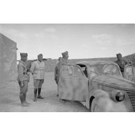 A l'intérieur du fort de Mechili, des officiers italiens, dont un officier général, posent puis parlent devant une voiture Fiat.