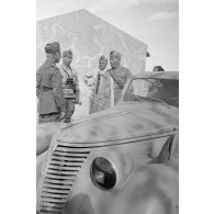 A l'intérieur du fort de Mechili, des officiers italiens, dont un officier général, posent puis parlent devant une voiture Fiat.