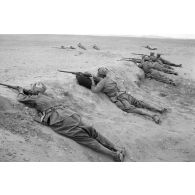 La ligne de fantassins, issus des troupes coloniales italiennes, allongés derrière un remblai en position de tir.