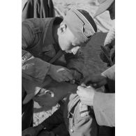 Un Oberleutnant, aidé par un Oberfeldwebel, soigne plusieurs blessés légers.