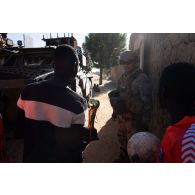 Un soldat du 16e bataillon de chasseurs à pied (16e BCP) discute avec des jeunes footballeurs dans les rues de Tessit, au Mali