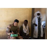 Un personnel du Service de santé des armées (SSA) reçoit un patient lors d'une aide médicale à la population (AMP) de Tessit, au Mali.
