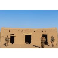 Des soldats du 16e bataillon de chasseurs à pied (16e BCP) accompagnés d'un soldat malien fouillent une habitation du village d'Argou, au Mali.