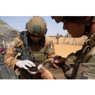 Des soldats du peloton de reconnaissance et d'intervention (PRI) contrôlent un téléphone portable trouvé dans une hutte sur la route de Tessit, au Mali.