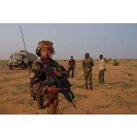 Le chef de la section appui du 3e régiment d'infanterie de marine (3e RIMa) accompagne un soldat malien dans la prise de contact avec des transporteurs de passage au nord de Bamba, au Mali.