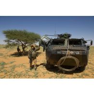 Des soldats de la section d'aide à l'engagement (SAE) du 1er régiment de hussards parachutistes (1er RHP) sécurisent le périmètre au pied de leur véhicule de l'avant blindé (VAB) T20-13 au nord de Bamba, au Mali.