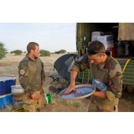 Des marsouins du 3e régiment d'infanteire de marine (RIMa) nettoient des ustensiles de cuisine pour la préparation du repas sur une zone de bivouac au nord de Bamba, au Mali.