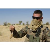 Un marsouin du 3e régiment d'infanterie de marine (3e RIMa) tient une souris par la queue lors d'une halte au nord de Bamba, au Mali.