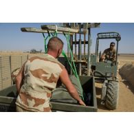 Un soldat de détachement de transit range une cuve souple dans son caisson de transport au moyen d'un engin de levage sur le camp de Tessalit, au Mali.