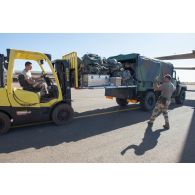 Le personnel du détachement de transit interarmées (DéTIA) charge le bagage des soldats à l'arrière d'un véhicule léger de reconnaissance et d'appui au moyen d'un chariot élévateur sur l'aéroport de Bamako, au Mali.