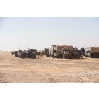 Des véhicules blindés légers (VBL) et des camions GBC-180 stationnent en base opérationnelle avancée temporaire (BOAT) lors d'une halte dans le désert malien.