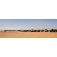 Les véhicules d'un convoi logistique stationnent en base opérationnelle avancée temporaire (BOAT) lors d'une halte dans le désert malien.
