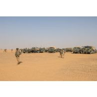 Les véhicules d'un convoi logistique stationnent en base opérationnelle avancée temporaire (BOAT) lors d'une halte dans le désert malien.