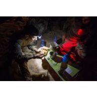 Des soldats mangent leur repas à la lueur de leur lampe frontale lors d'un bivouac dans la région de Tombouctou, au Mali.