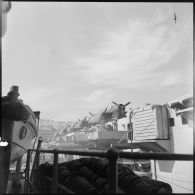 Photographie du pont d'envol du porte-avions Arromanches au mouillage dans la rade d'Alger, depuis l'un des garde-corps du croiseur Georges Leygues.