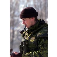 Un militaire danois avec ses jumelles et son talkie-walkie fumant la pipe.