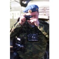 Un militaire russe bardé d'appareils photographiques (Canon, Zenit) prend une photo.