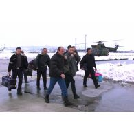 Les membres de la sécurité civile kosovare (KPC) descendent d'un Puma et marchent sur la piste d'atterrissage.