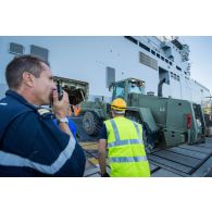 Une enseigne de vaisseau de 1re classe encadre le chargement d'un bulldozer du Génie à bord du bâtiment de projection et de commandement (BPC) Le Tonnerre à Toulon.