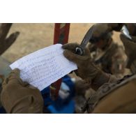 Un soldat du peloton de reconnaissance et d'intervention (PRI) découvre un message écrit en arabe dans une cache d'armes lors d'une reconnaissance de la région de Tessit, au Mali.