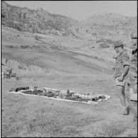 Le colonel Meyer, commandant le 1er régiment de chasseurs parachutistes (RCP), devant l'arsenal pris aux rebelles, dans le paysage du Djebel.