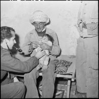 Le lieutenant médecin du 62ème bataillon du génie donne des soins à un enfant du douar Imama.