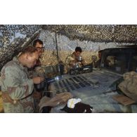 Pause café sur le capot d'un véhicule Hummer américain sous un filet de camouflage sur un poste en ZDO (zone de déploiement opérationnel) Olive.