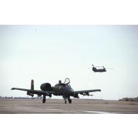 Un avion d'appui rapproché Fairchild A-10 Thunderbolt-II est survolé par un hélicoptère d'assaut Boeing Vertol Ch-47 Chinook sur la piste de la base air américaine de CRK (camp du roi Khaled).