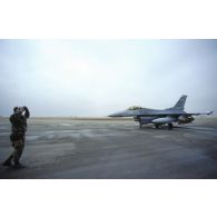 Un mécanicien de piste américain guide un avion de combat F-16 sur la piste de la base américaine de CRK (camp du roi Khaled).