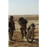 Perception de la nouvelle tenue sable par un soldat du 4e RD (régiment de dragons) en ZDO (zone de déploiement opérationnel) Olive, à côté d'une motocyclette 80 cm3 SX Peugeot.