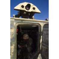 En ZDO (zone de déploiement opérationnel) Olive, la porte arrière ouverte d'un blindé M901 américain laisse deviner un soldat assis.