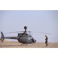 Portrait de deux militaires américains. En arrière-plan, un hélicoptère américain de reconnaissance et d'observation Bell OH-58 D Kiowa dans le désert en ZDO (zone de déploiement opérationnel) Olive.