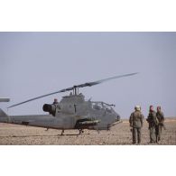 Hélicoptère de combat américain Bell-209 Huey Cobra dans le désert en ZDO (zone de déploiement opérationnel) Olive et groupe de militaires américains.