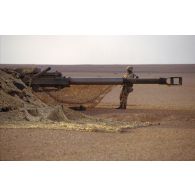 En ZDO (zone de déploiement opérationnel) Olive, un soldat tend un filet de camouflage sur un obusier de 155 mm M198 du 8e régiment d'artillerie américain lors d'un exercice de mise en batterie.