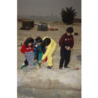 Des enfants koweitiens jouent sur la plage et manipulent des mines antipersonnel irakiennes désamorcées lors de la présentation à la population civile du travail de déminage accompli sur les plages de Koweit City.