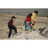 Des enfants koweitiens jouent sur la plage et manipulent des munitions irakiennes désamorcées lors de la présentation à la population civile du travail de déminage accompli sur les plages de Koweit City.