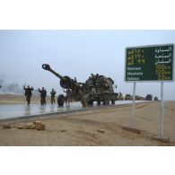 Sur l'axe Texas un camion américain tractant un obusier de 155 mm M198 croise des soldats irakiens qui se rendent.