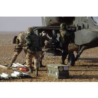 En ZDO (zone de déploiement opérationnel) Olive, des soldats ravitailllent en carburant et approvisionnent les paniers de roquettes de 70 mm d'un hélicoptère de combat américain Hughes-AH 64 Apache dans le désert.