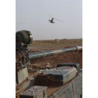 Un hélicoptère de combat Gazelle Hot du 5e RHC survole un blindé de reconnaissance AMX-10 RC dans le désert. Le Gazelle vient de lancer un leurre ; au premier plan gît un épave de char de combat T-55 irakien détruit.