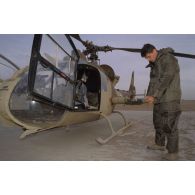 Un membre de l'équipage d'un d'hélicoptère de combat Gazelle Hot du 5e RHC revêt la tenue S-3P (survêtement de protection à port permanent) lors d'un exercice NBC.