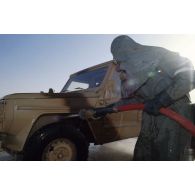 Exercice NBC de décontamination de véhicule Peugeot P4 par des soldats en tenue 66. Etape de rinçage.